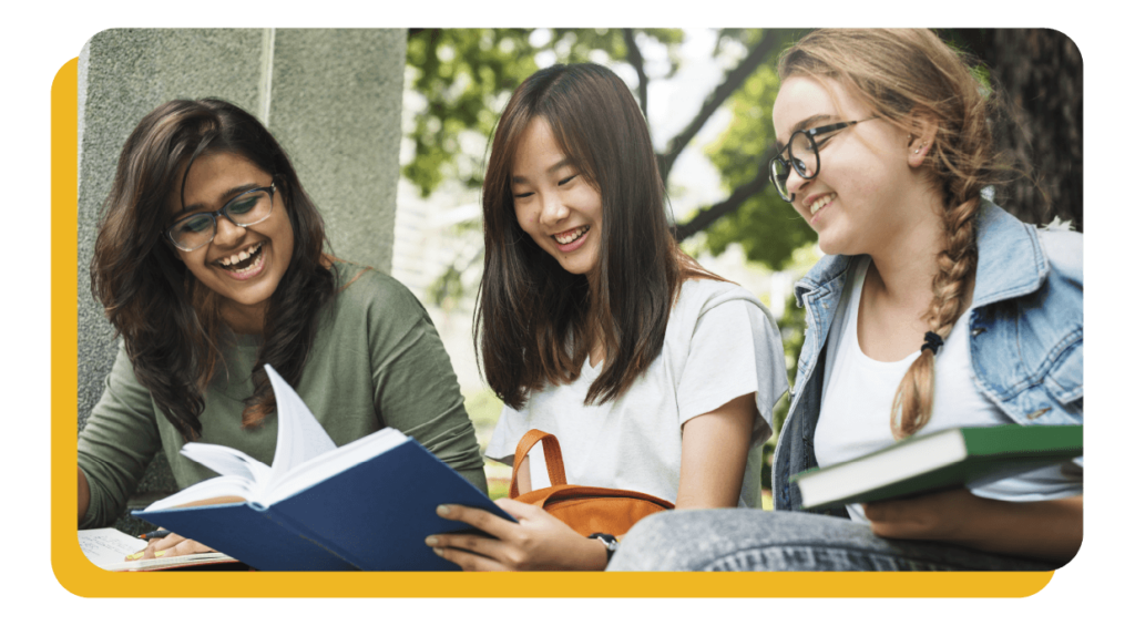 Three happy students looking at a book